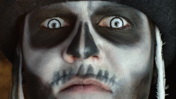 Close-up of Scary Man Face in Skull Halloween Makeup of Skeleton Showing Dirty Teeth and Tongue alt