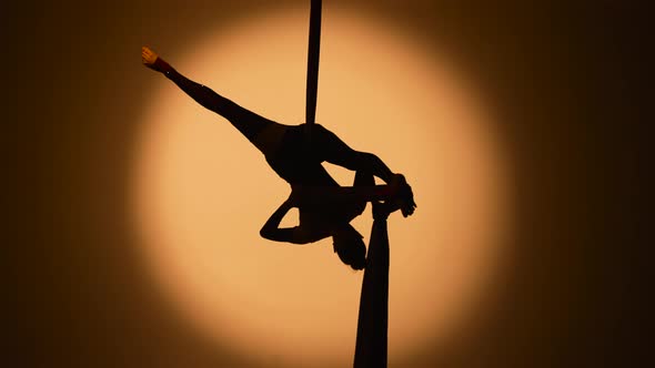 Silhouette of a Young Woman Spins Hanging Upside Down and Twine on Airy Silk alt