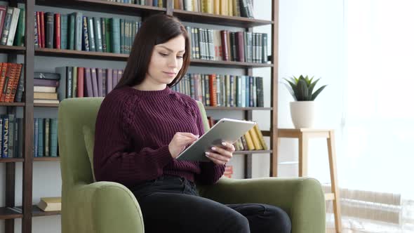 Woman Sitting on Casual Chair Browsing Internet on Tablet alt