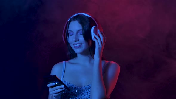 Portrait of Charming Young Woman Enjoying Music From Smartphone in Big Red Headphones. Close Up alt