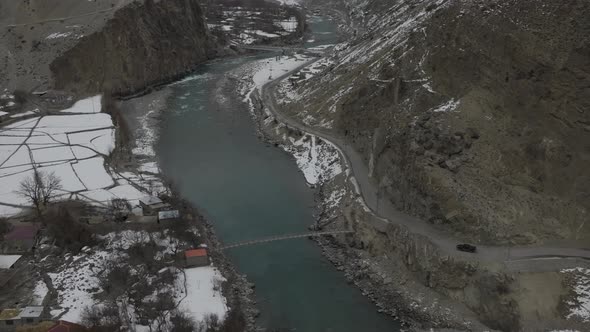 Aerial Drone Surveillance Footage Of Black Car Approach Bend Beside River In Hunza Valley. Dolly Zoo alt