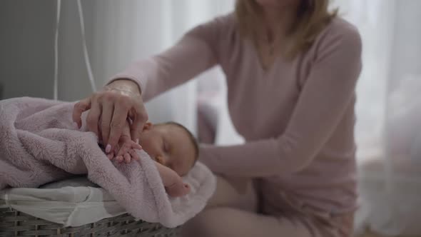Sleeping Baby Girl in Basket with Unrecognizable Woman Touching Little Hand in Slow Motion alt