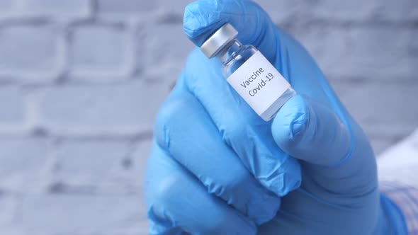 Doctor Hand in Gloves Holding Coronavirus Vaccine, Close Up alt