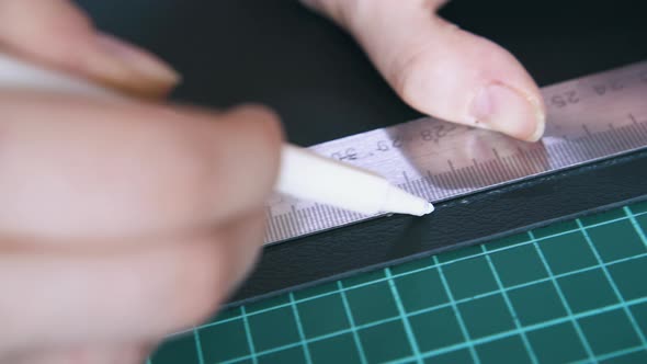 Skilled Tailor Draws Line on Leather Cloth with White Pen alt