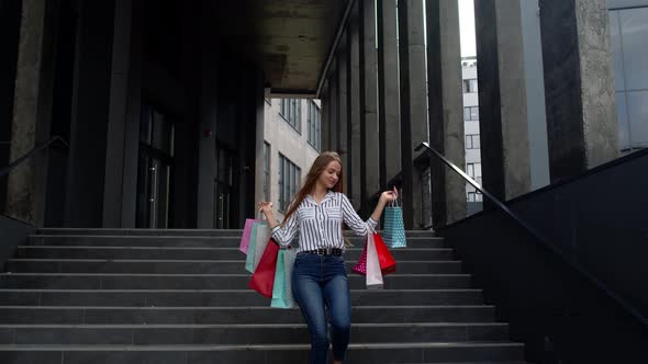 Smiling Girl Walking From Centre Mall with Shopping Bags, Happy with Low Prices on Black Friday alt