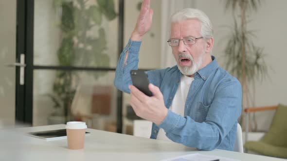 Senior Old Man Reacting to Loss on Smartphone in Office alt