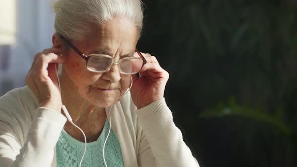 Senior Woman Putting Earphones for Video Call