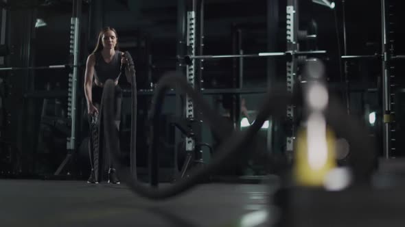 Young Woman Performs Exercises with Battle Ropes Endurance Training in the Gym  Slow Motion alt
