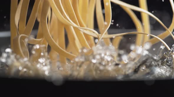 Throwing linguine noodle in water. Slow Motion. alt
