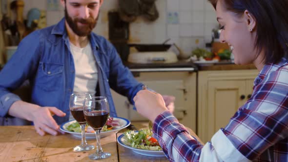 Young couple talking while having meal in kitchen alt