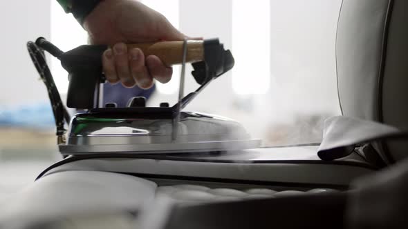 Close Up Worker Smoothes Skin in Car or Helicopter or Business Jet with Special Iron Steam Comes Out alt