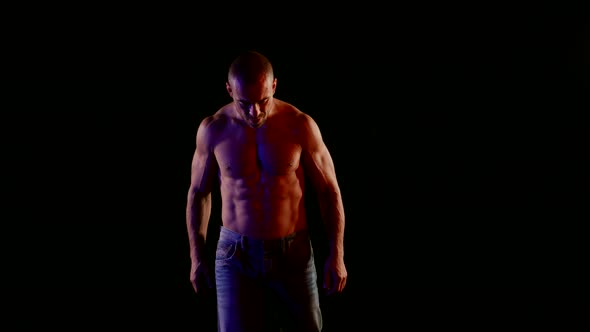 a Muscular Bald Man with a Bare Torso and Jeans Tilted Head and Walks Forward Then Raises Fists to alt