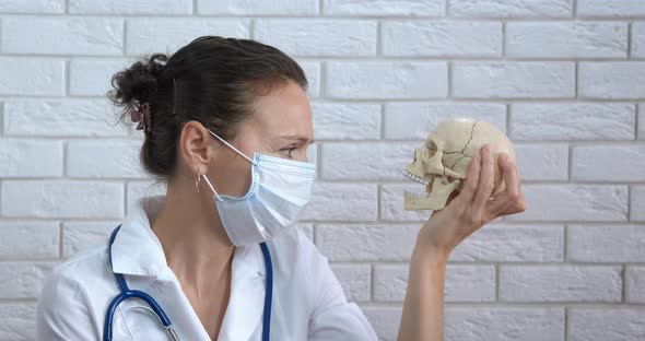 Doctor look at skull view. A view of a doctor in mask with a human skull. alt