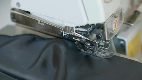 Closeup the Overstitching Machine Passes the Edges of the Black Fabric in Slow Motion alt