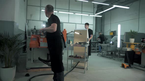 Team of professional workers maintain a huge numerically controlled machine at a complex metal const