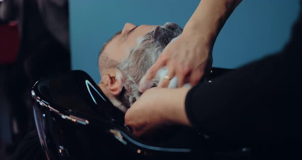 Hairdresser Shampooing Client's Hair a Lot of Foam on His Head alt