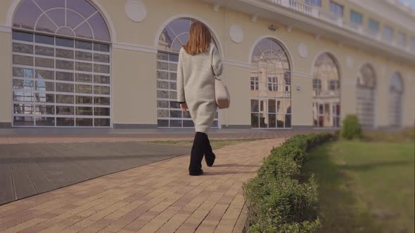 Woman Walking in a Park in Trendy Clothes. alt