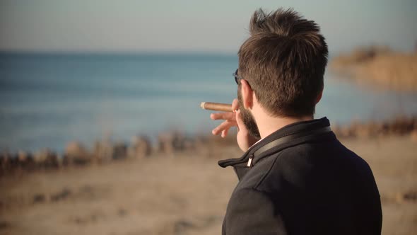 Thoughtful Serious Man Relaxing On Autumn Park And Smoking. Man Relaxing Outdoor And Smoking Sigaret alt