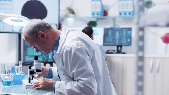 Dolly Shot of Adult Doctor or Researcher Using a Microscope alt