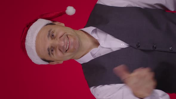 Vertical Shot Christmas Wreath Flies Into Frame and Falls on Neck Happy 40s Man in Santa Hat