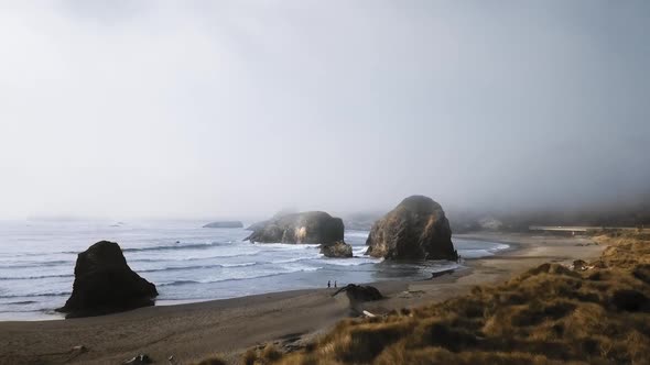 The drone camera is approaching a couple walking along the shore (Ariya's Beach, Oregon, USA) alt