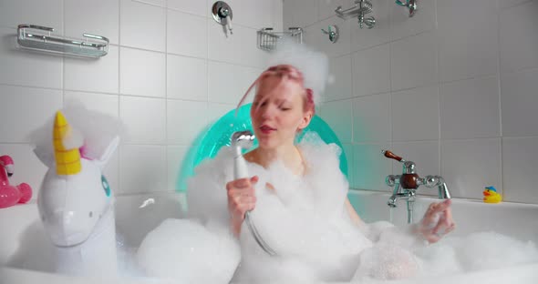 Funny Woman Sits in Bath Filled with Foam Holds Shower Singing Songs alt