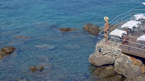 A woman at a restaurant over the Mediterranean Sea in a luxury resort town in Italy, Europe alt