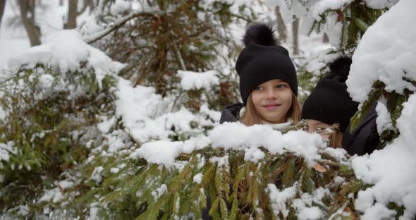 Two Girls Playing Hide And Seek In The Snow