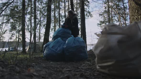 Young Woman Altruist Collecting Trash in the Forest