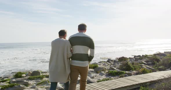 Caucasian couple enjoying free time by sea on sunny day walking path alt