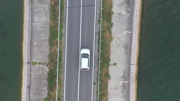 Top View of White Car Rides Through Dam Route alt