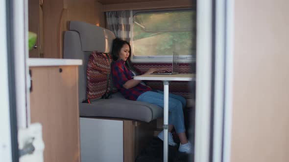 Asian Female Working at a Laptop While Sitting in a Car Typing Text and Remote Work in Nature alt