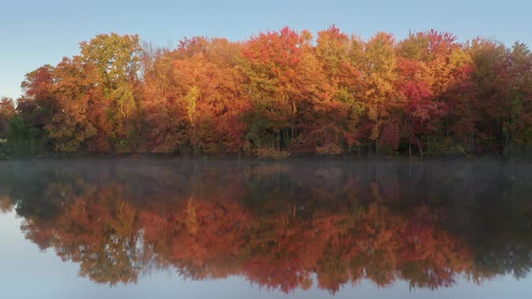 Cinematic Fall Foliage Forest Reflecting in the Still Surface of Lake Water alt
