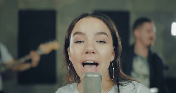 Young Pretty Girl Emotionally Singing a Song at the Microphone alt