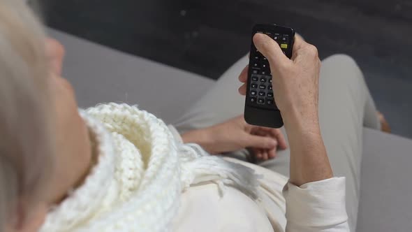 Sick Elderly Lady Holding TV Remote Controller, Switching Channels at Home