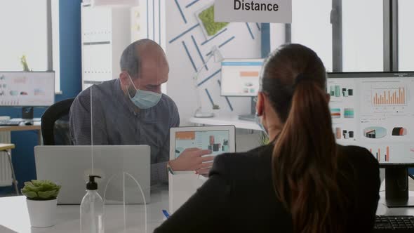 Coworkers with Protective Face Masks Talking About Management Statistics alt