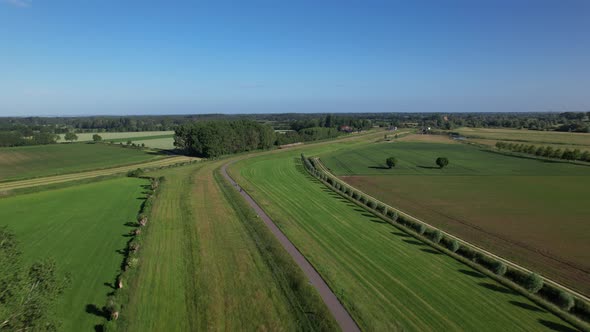 Dutch river valley landscape aerial following the embankment with a road on top meandering through t alt