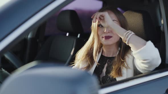 Desperate Woman Can't Start Auto Smiles and Looks at Window alt