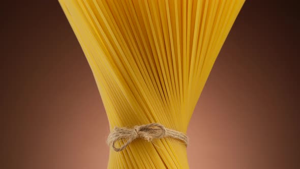 Authentic Italian spaghetti pasta on brown background, rotate. Vegan, vegetarian food alt
