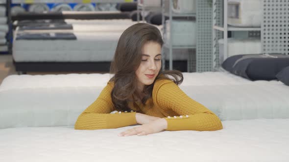 Beautiful Happy Woman Examining Orthopedic Mattress on Sale alt