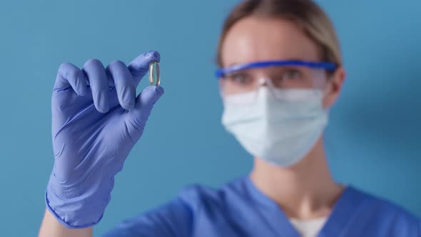 Medical practitioner holding up and inspecting a cupsule at work. Healthcare concept