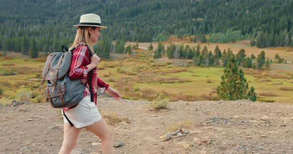 Woman Is Hiking By the Autumn Nature with Green Pine Trees on Background alt