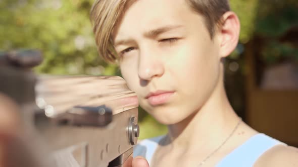 Portrait of a Funny Boy Reloading a Kalashnikov Assault Rifle Outdoors Children's Games