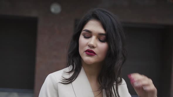 Passionate Brunette with Tempting Makeup Poses Thoughtfully Outdoors alt