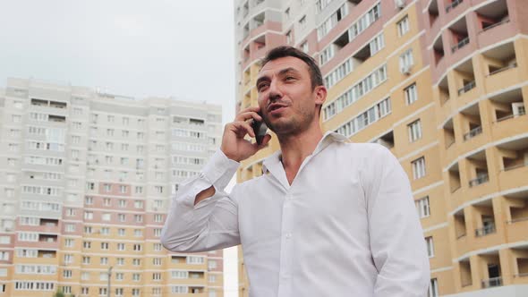 A Businessman in a White Shirt Speaks on the Phone with a Smile alt
