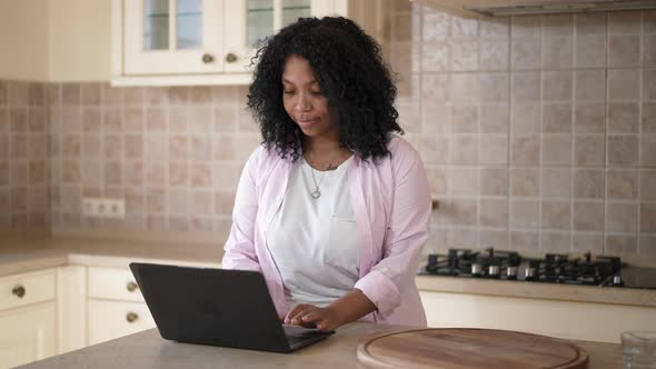 Portrait of Concentrated Intelligent African American Young Woman Typing on Laptop Keyboard Thinking alt