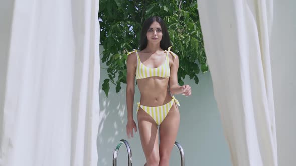 woman in swimsuit walking out of the pool.