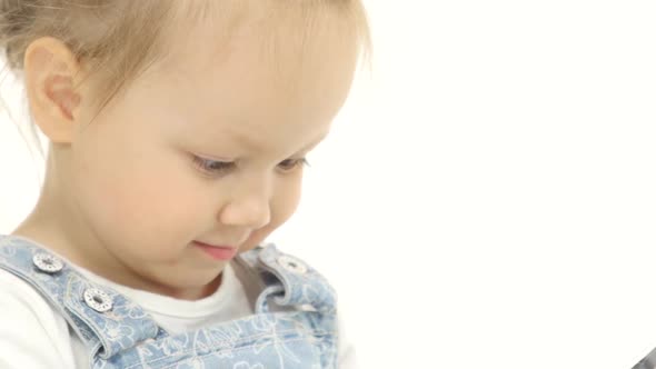 Little Child Looks Interesting Pictures on the Tablet. White Background alt