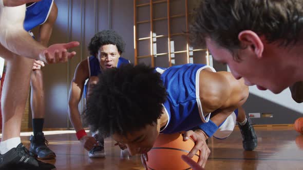 Diverse male basketball team wearing blue sportswear and doing push ups alt