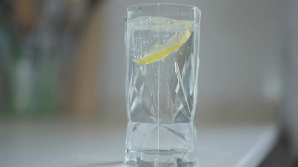 Lemon Falling in Water Spilling Liquid on White Table Indoors alt